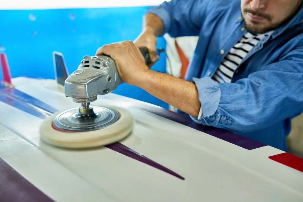 Tanned Man Polishing Surfing Board in Workshop
